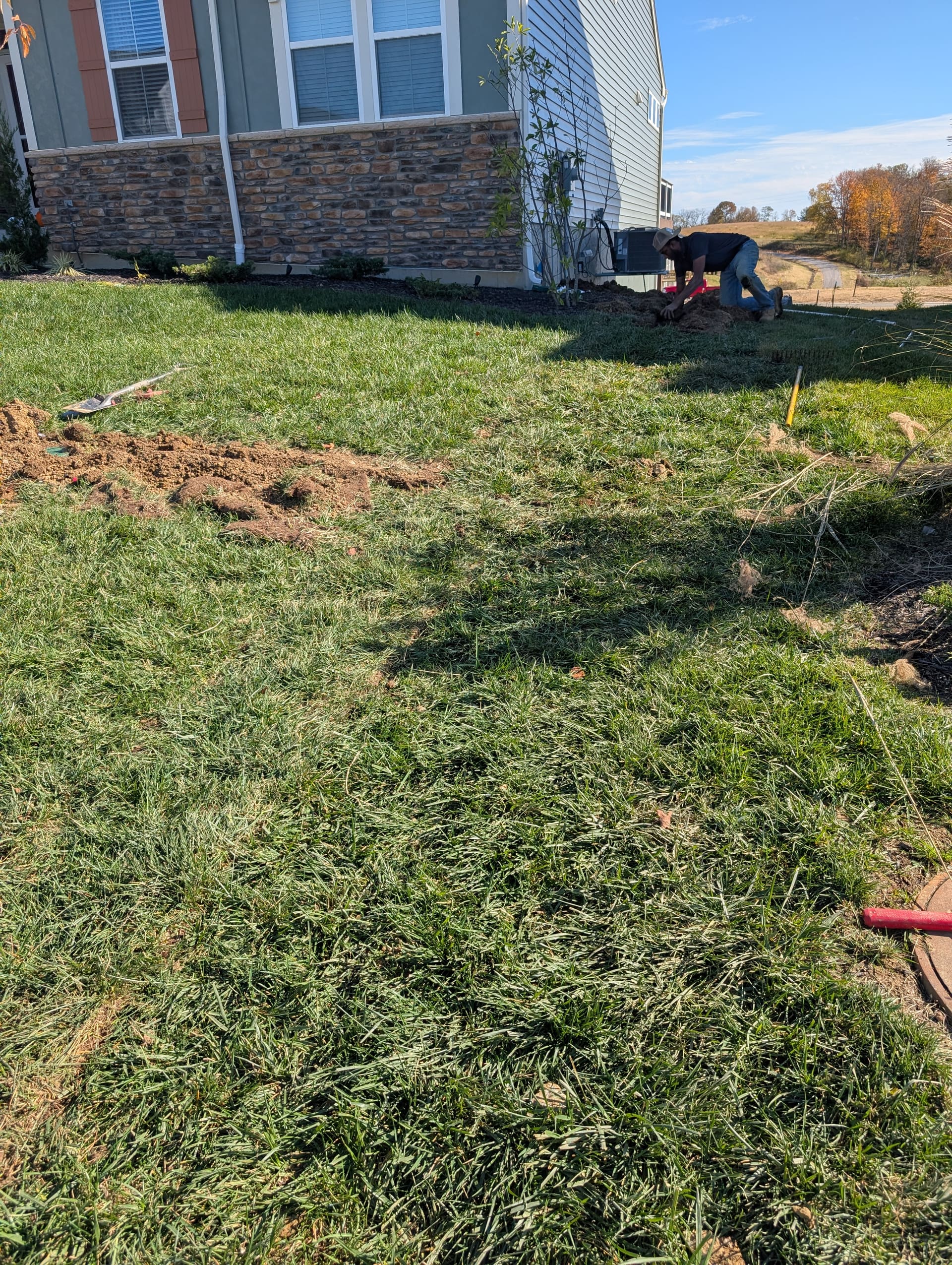Irrigation line being set into a narrow trench beside a home during installation.