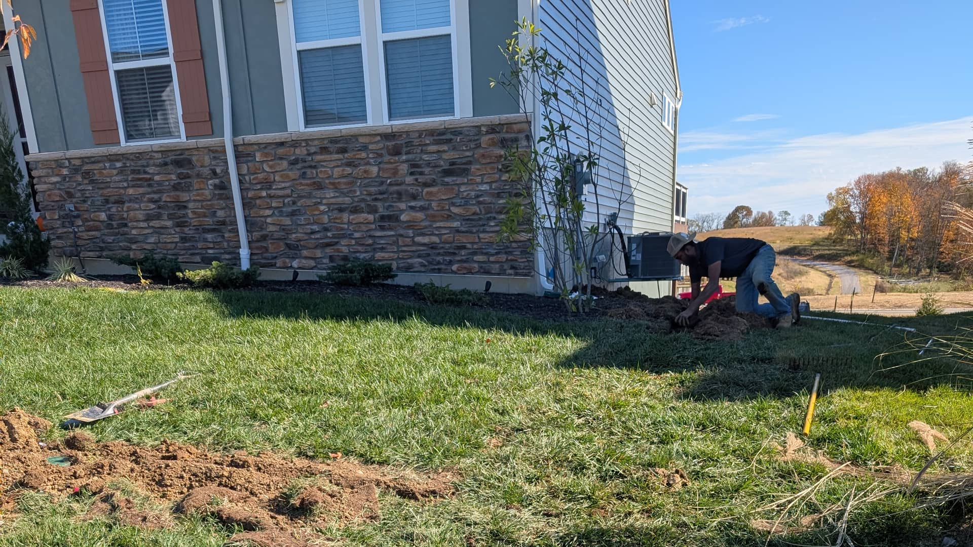 Irrigation line being set into a narrow trench beside a home during installation.